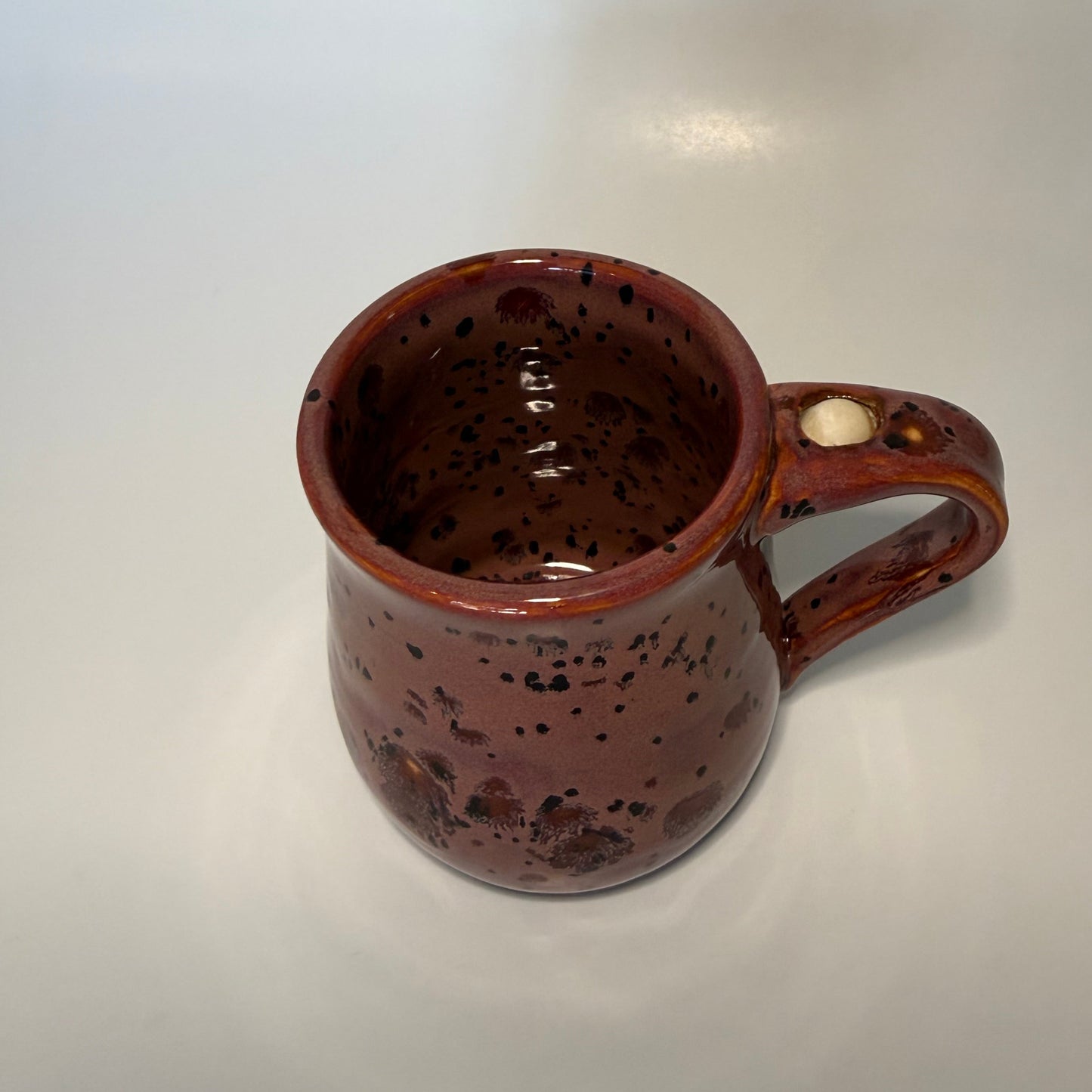 Red with brown speckled mug with fidget ball on handle 