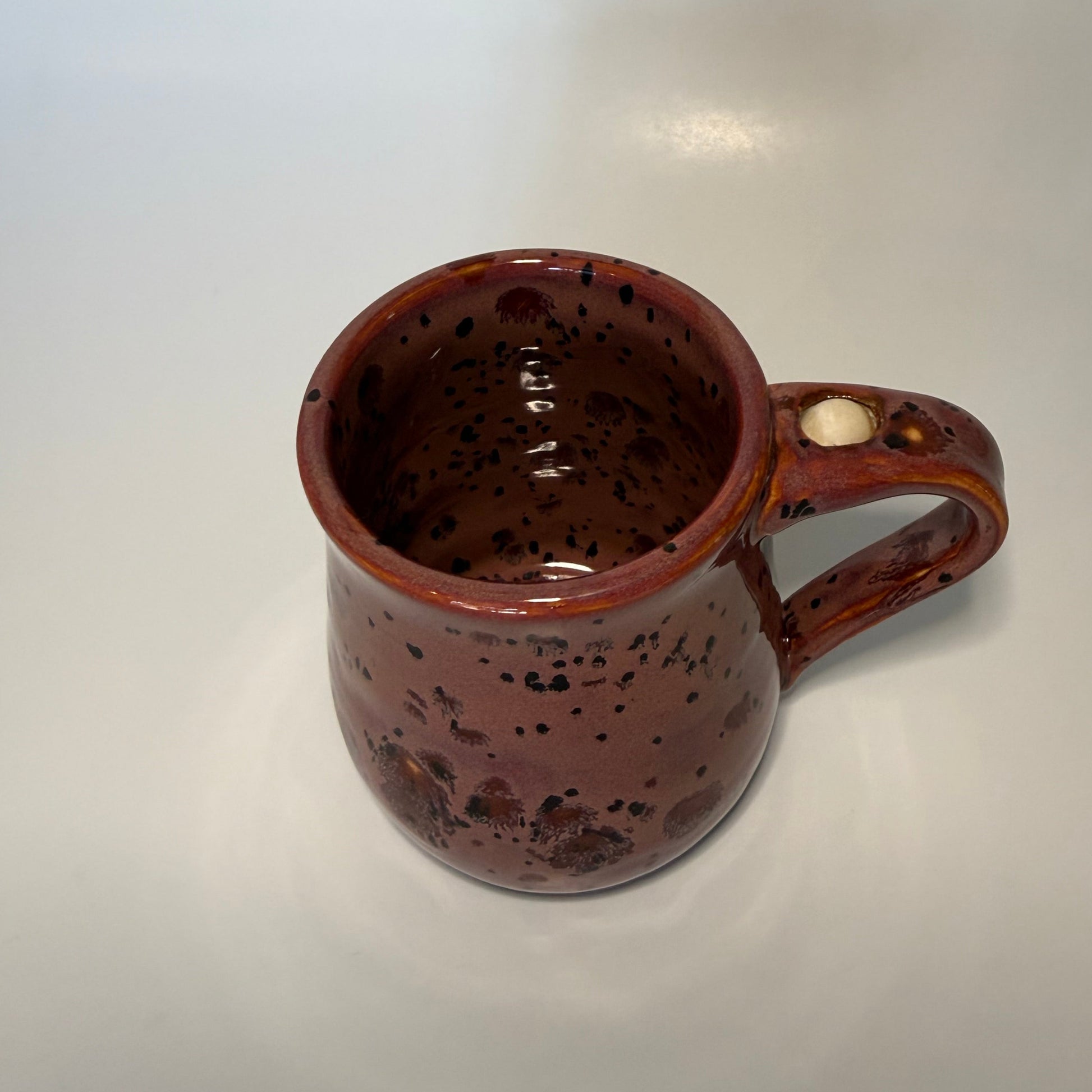 Red with brown speckled mug with fidget ball on handle 